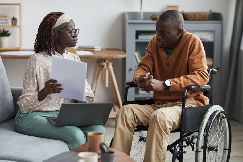 social worker talking with man in wheelchair